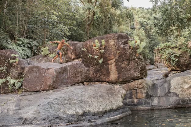 A guy jumps from a reef into the water